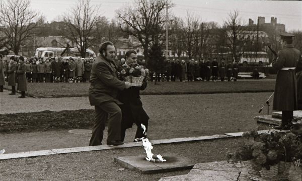 Foto: Enno Kapstas, asutuste esindajad lillekorve toomas, Suure Sotsialistliku Oktoobrirevolutsiooni 60. aastapäeva miiting vennaskalmistul, 3.11.1977, RM Fn 1543:3410, Virumaa Muuseumid SA, http://www.muis.ee/museaalview/2349780. 